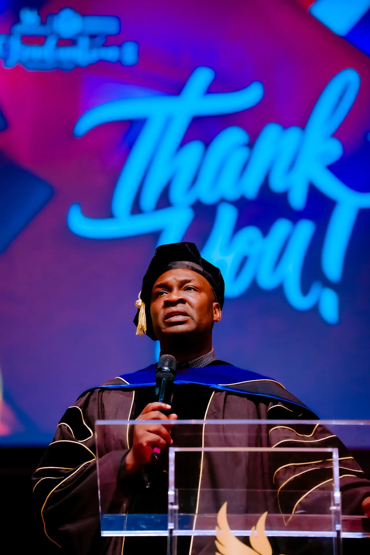 Apostle Joshua Selman giving a graduation address in academic regalia